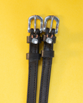 Black leather ManeJane spur straps with silver buckles and grey donkey face charms on yellow