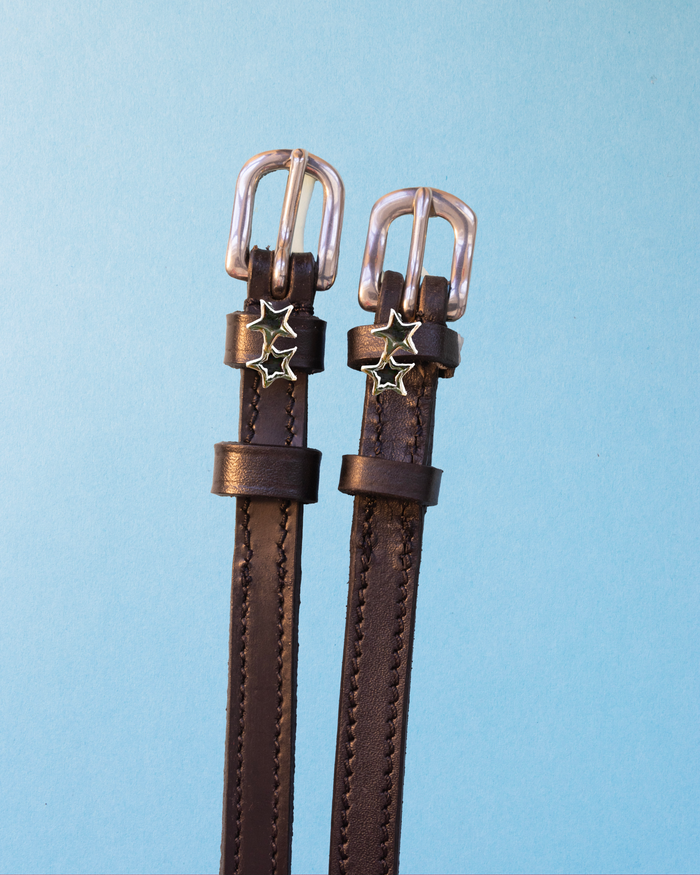 Dark brown leather double star spur straps with silver buckles on light blue