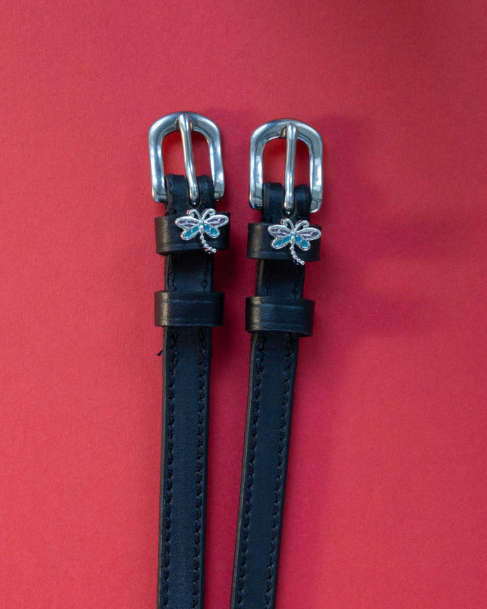 Dragonfly ManeJane spur straps with the signature Dragonfly charm, shown on a red background
