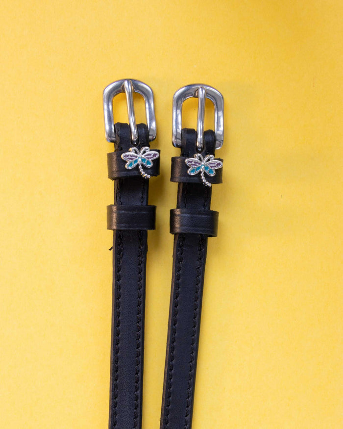 Dragonfly ManeJane spur straps with the signature Dragonfly charm, shown on a yellow background