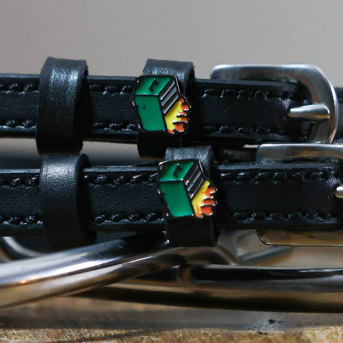 Close-up of green dumpster fire enamel charms on black leather spur strap keepers