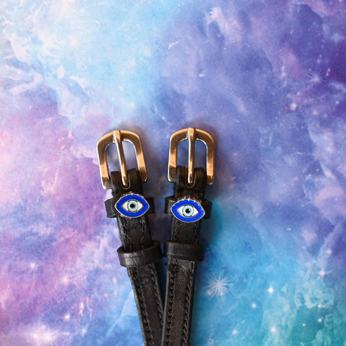 Black leather evil eye spur straps with brass buckles on a galaxy print background