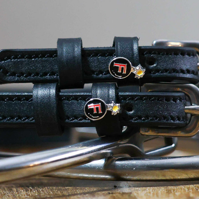 Close-up of red F-bomb charms on black leather ManeJane spur straps over spur hardware
