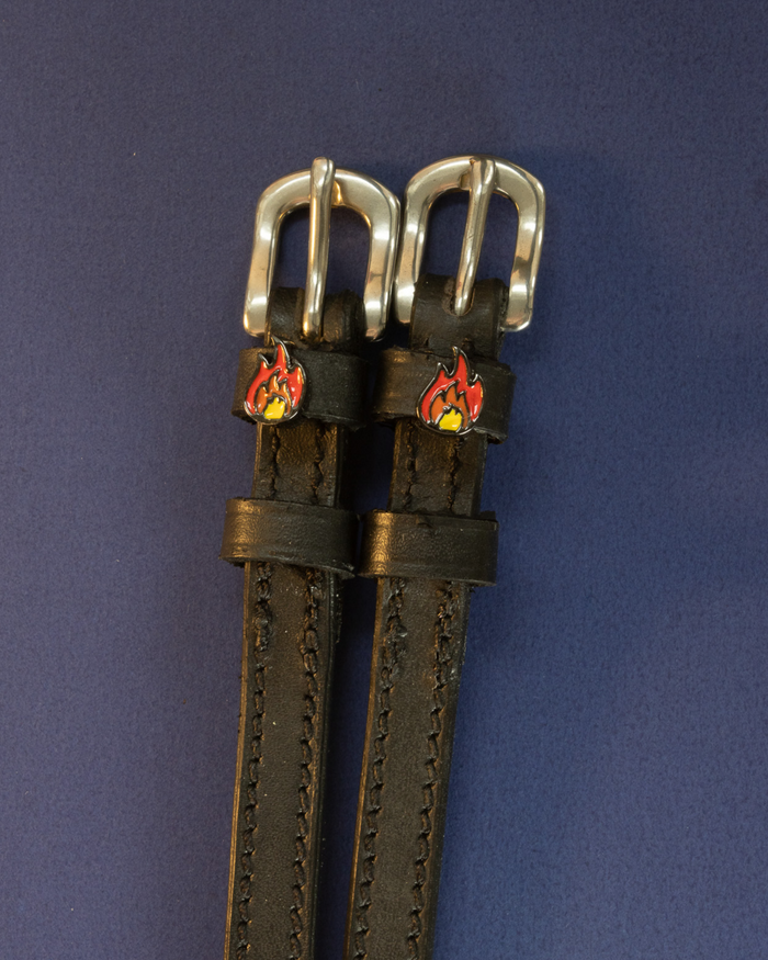 Pair of black leather flame spur straps with silver buckles on a navy background