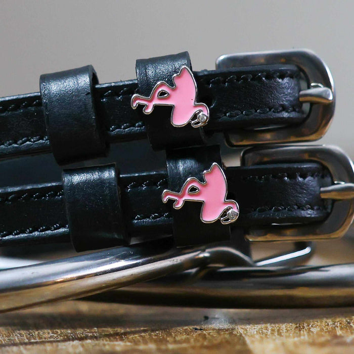 Close-up of pink enamel flamingo charms on black leather spur strap keepers