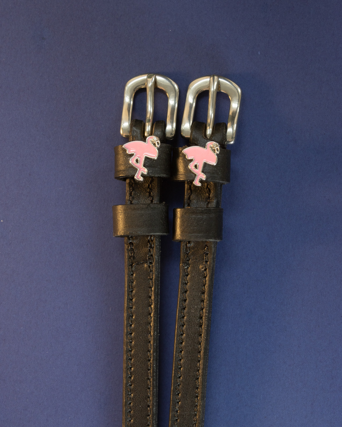 Pair of black leather flamingo spur straps flat-laid on a navy background