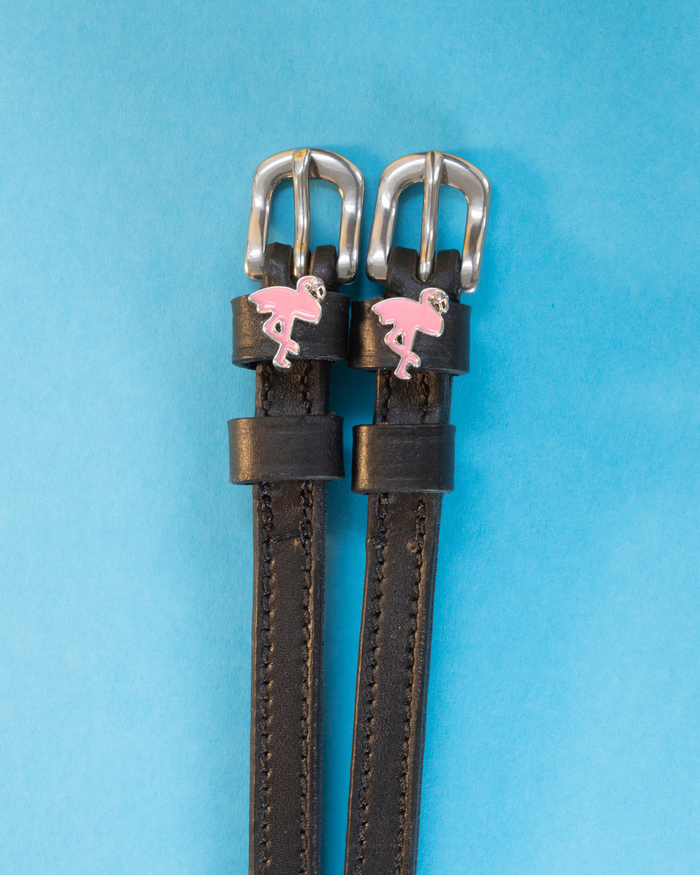 Black leather flamingo charm spur straps on a bright blue background