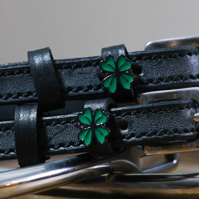 Close-up of green enamel four leaf clover charms on black leather ManeJane spur straps