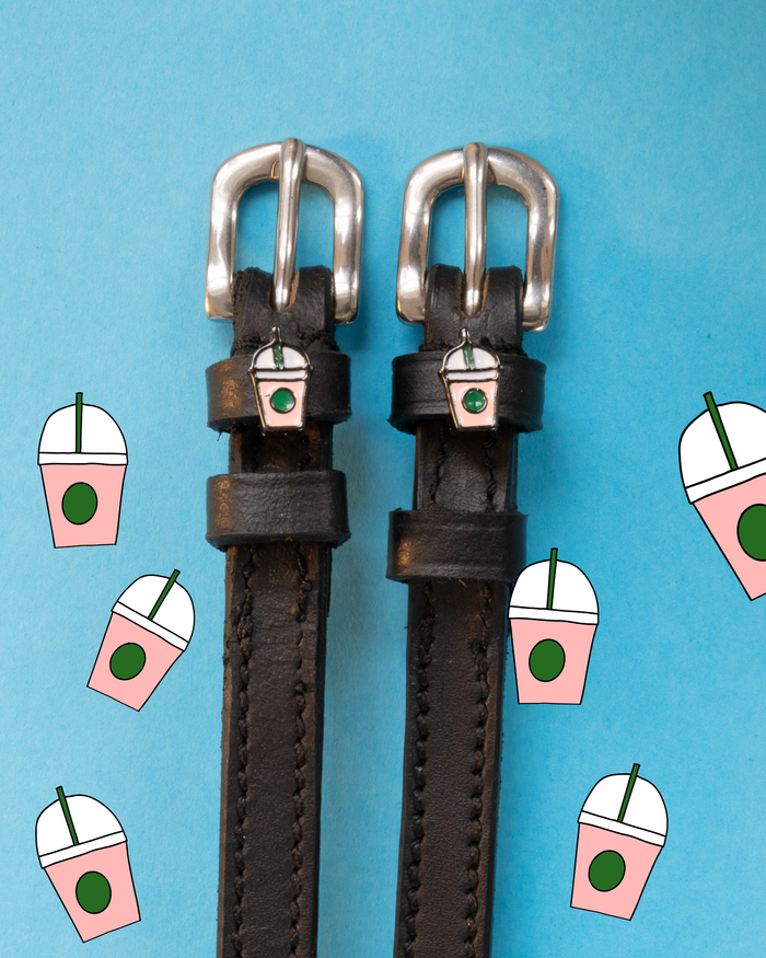 Dark leather frappe spur straps flat-laid on a blue iced-coffee icon backdrop