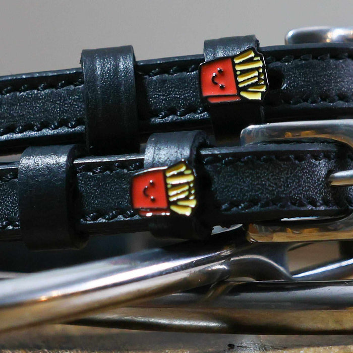 Close-up of smiling French fry charms on black leather spur straps over spur hardware