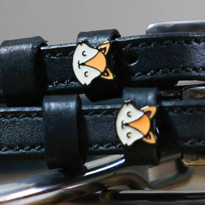 Close-up of orange fox face charms on the keepers of black leather spur straps