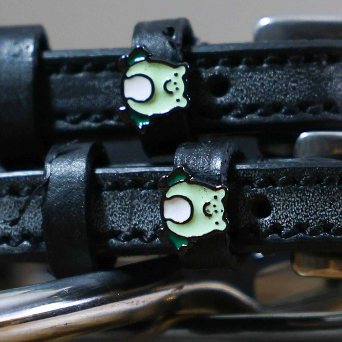 Close-up of green enamel frog charms on the keepers of black leather ManeJane spur straps