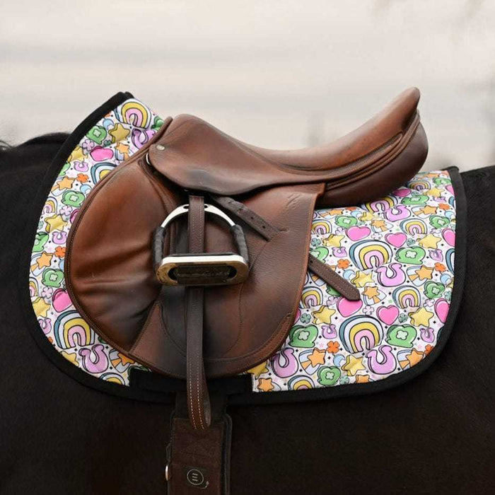 Brown leather saddle on horse with colorful Lucky Equestrian Bundle Full O’ Luck saddle pad featuring clovers, rainbows, and horseshoes