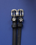 Black leather ManeJane spur straps with silver 'Giddy Up' star charms on a blue background