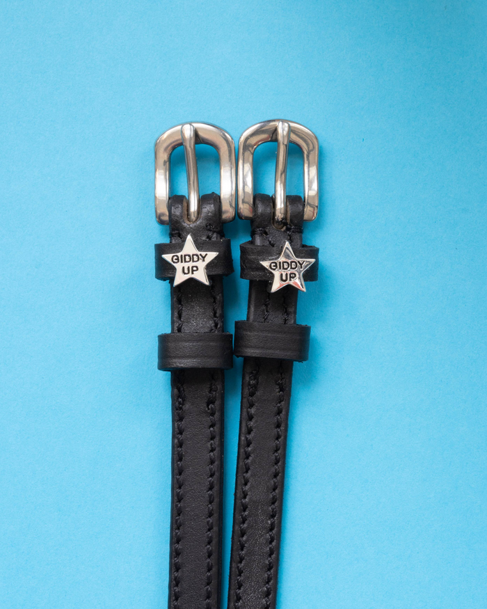 Pair of black leather 'Giddy Up' star spur straps with silver buckles on bright blue