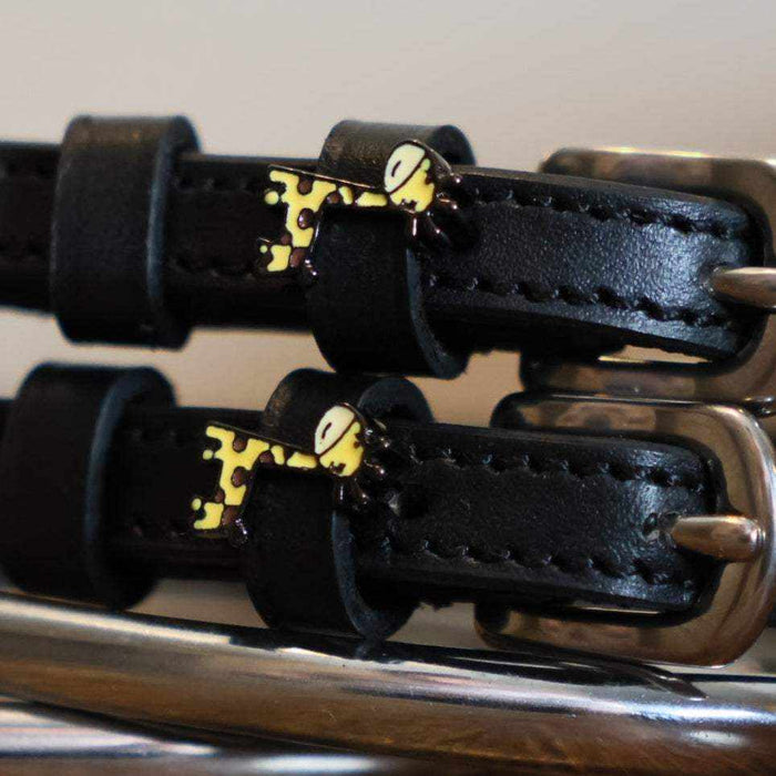 Close-up of yellow giraffe charms on black leather spur straps over spur hardware