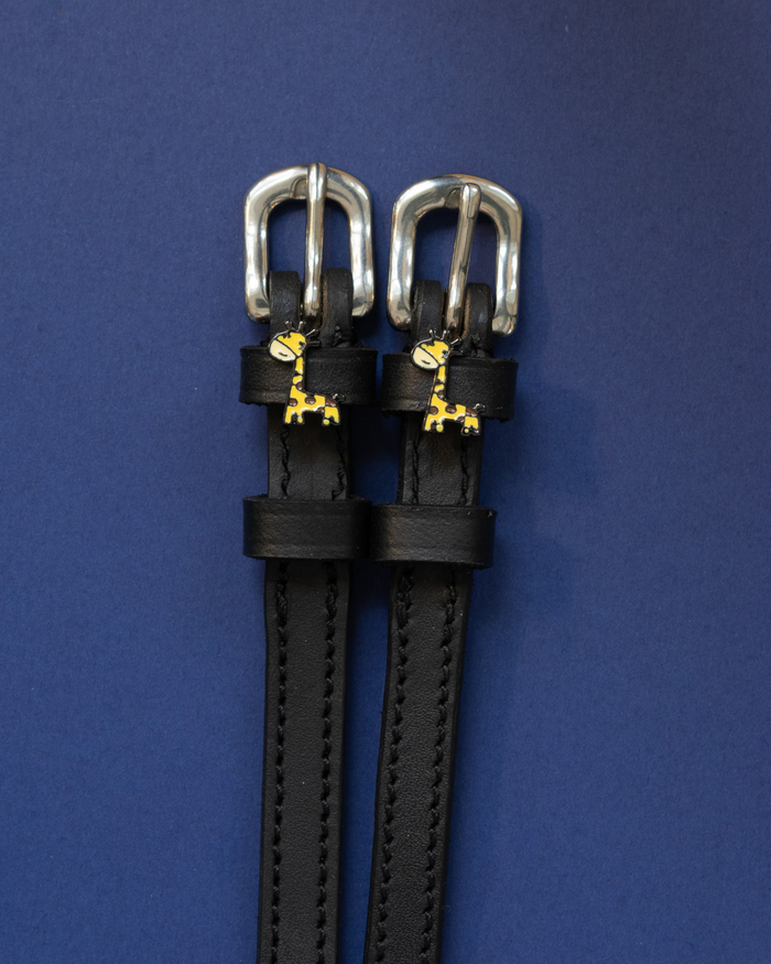 Pair of black leather Giraffe spur straps with silver buckles on a navy background