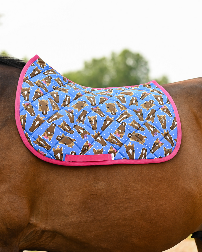 Hairy Styles saddle pad in bright blue with hot pink trim, worn saddle-free on a bay horse outdoors