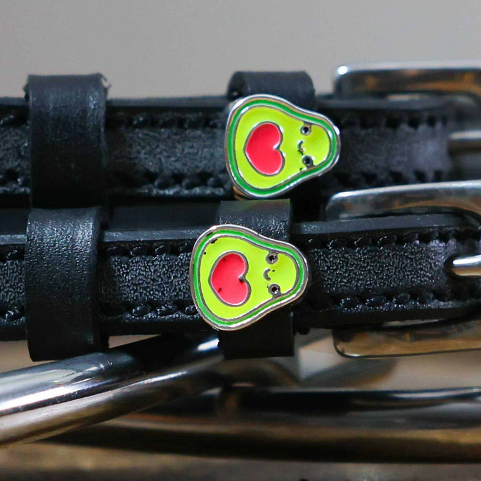 Close-up of green avocado charms with red heart pits on black spur strap keepers