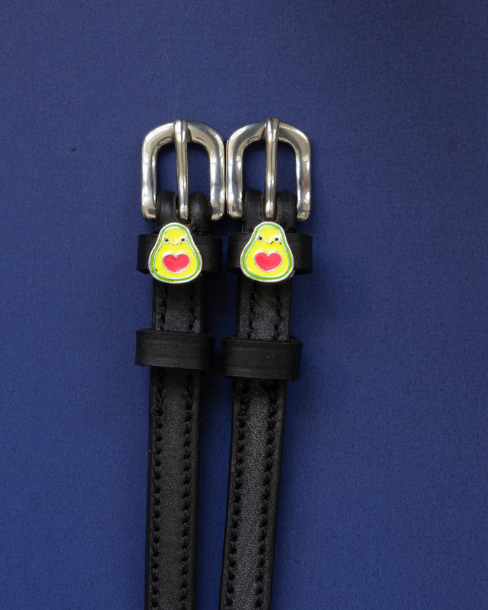 Black leather avocado spur straps with silver buckles on a navy blue background