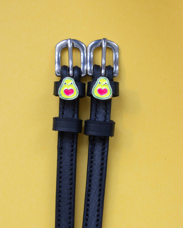 Pair of black leather avocado spur straps on a yellow background