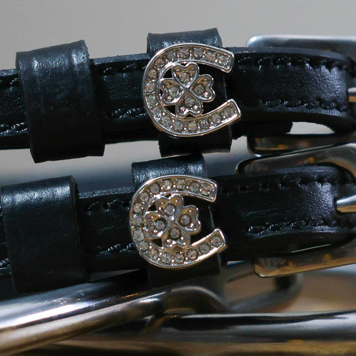 Close-up of rhinestone horseshoe-and-clover charms on black leather spur strap keepers