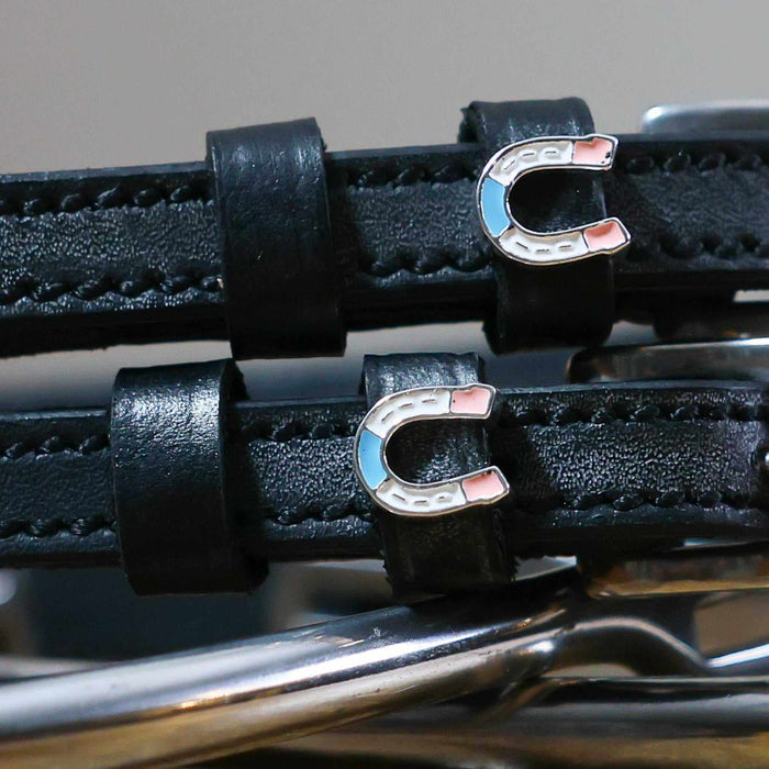 Close-up of blue-and-pink enamel horseshoe charms on black leather spur strap keepers