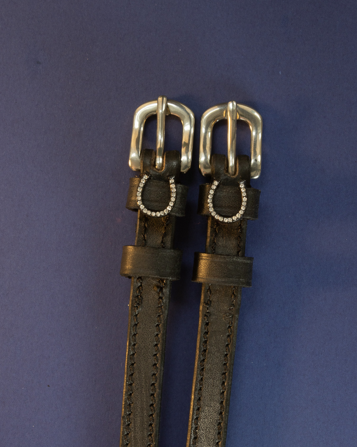 Black leather ManeJane spur straps with silver buckles and crystal horseshoe charms on navy