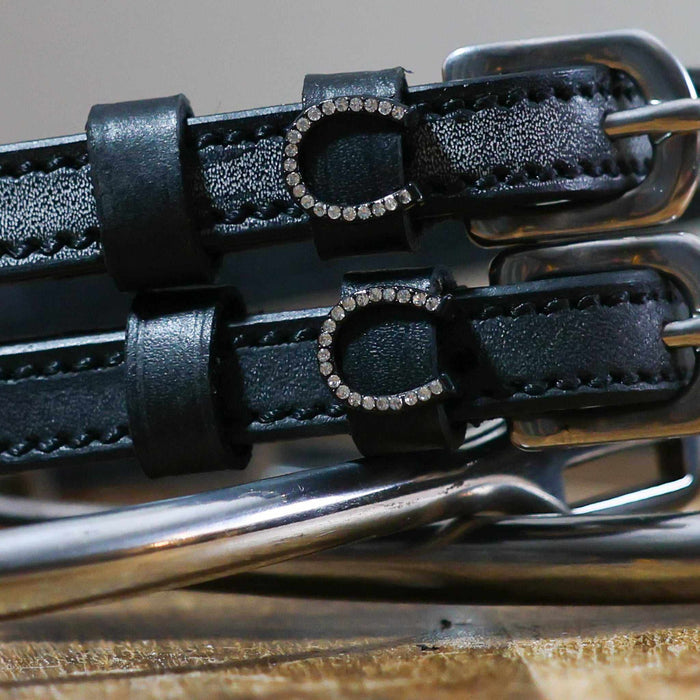 Close-up of rhinestone horseshoe charms on black leather ManeJane spur strap keepers