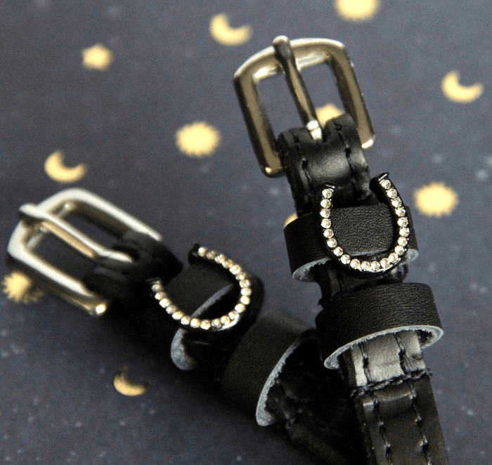 Angled close-up of crystal horseshoe spur straps on a starry moon-print backdrop