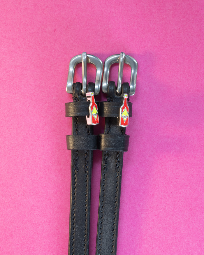 Black leather ManeJane spur straps with hot sauce bottle charms on hot pink