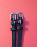 Black leather ManeJane spur straps with ice cream cone charms on a coral background