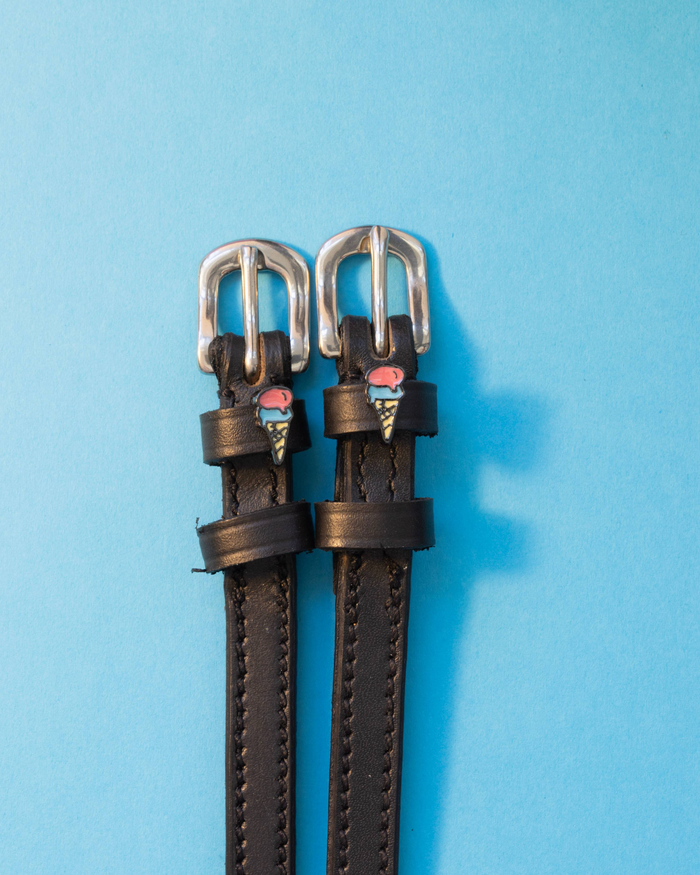 Black leather ice cream cone charm spur straps with silver buckles on light blue