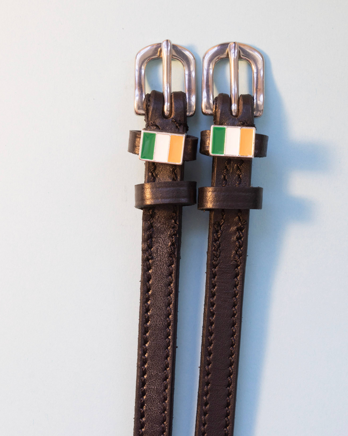 Brown leather ManeJane Irish flag spur straps with silver buckles, pale blue backdrop