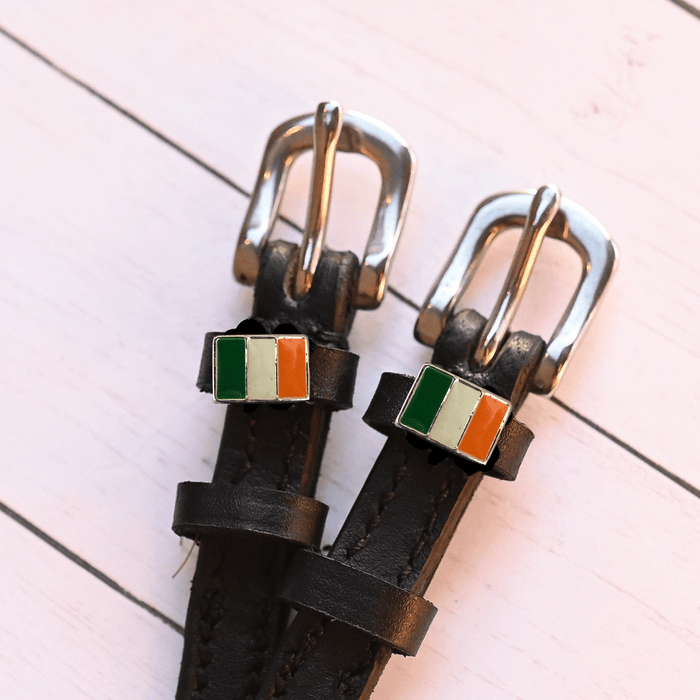 Angled close-up of Irish flag charms on ManeJane spur straps over pink planks