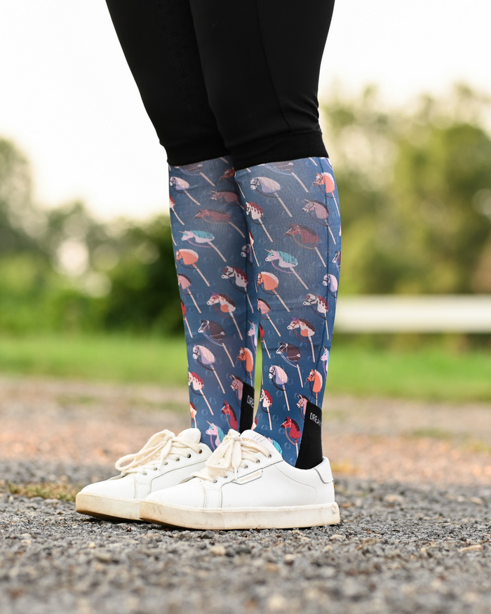 It's Not a Hobby riding boot socks styled over breeches, slate blue with hobby horses on wooden sticks