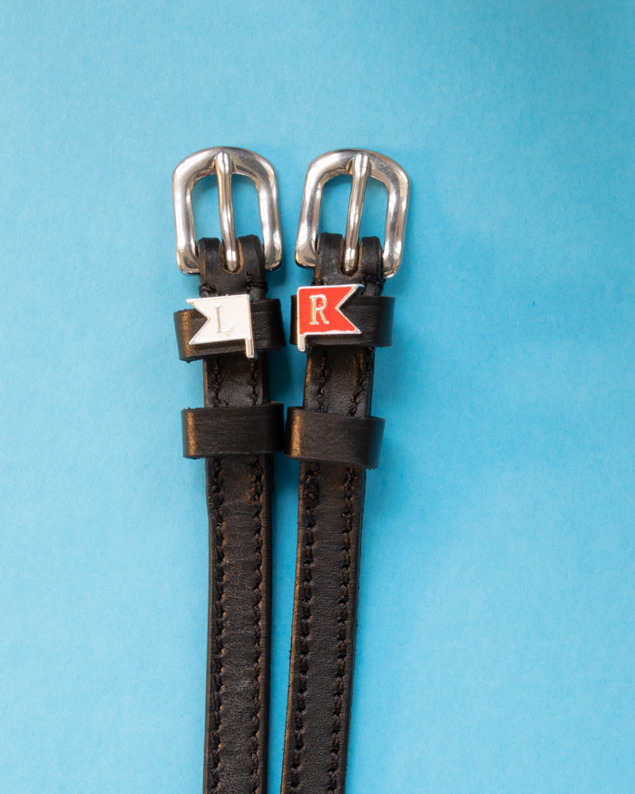 Black leather spur straps with silver buckles and white L and red R jump-flag charms on blue