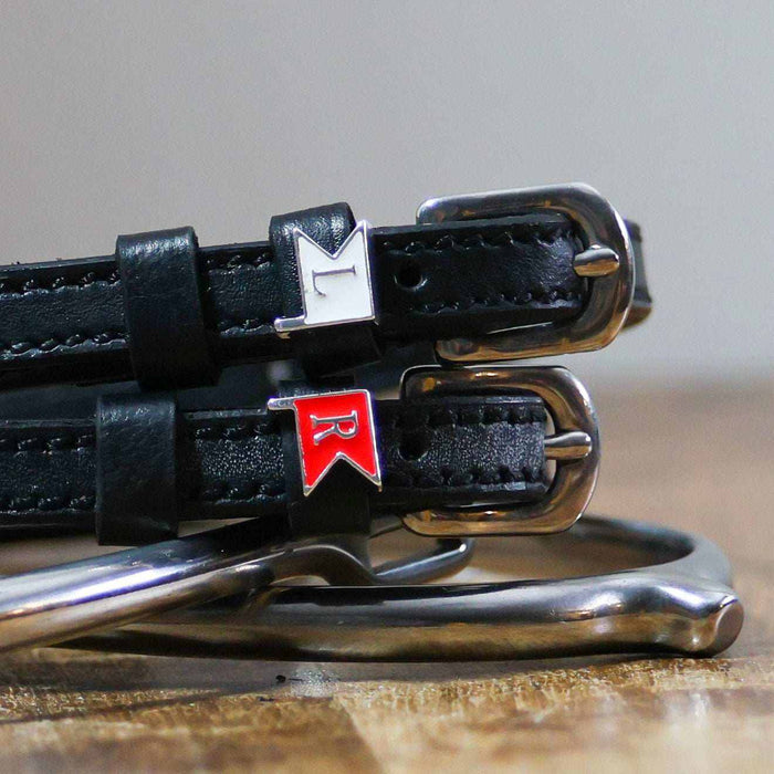 Close-up of white L and red R jump-flag charms on black leather ManeJane spur straps
