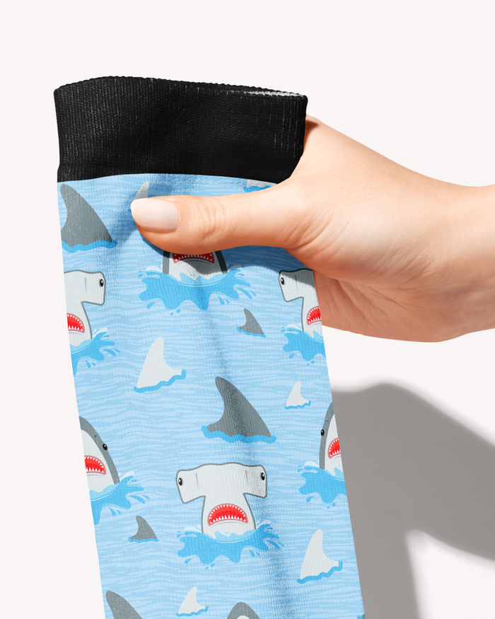 Close-up of the Shark Week boot sock pattern with grinning sharks and grey fins breaching blue waves