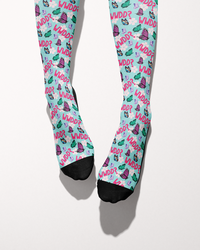 What Would Dolly Do? socks shown on bare feet with black toe and heel accents, mint green butterfly print