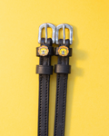Black leather ManeJane spur straps with cartoon lion face charms and silver buckles on yellow