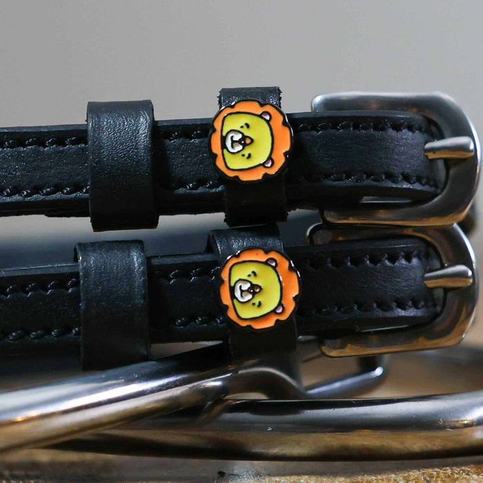 Close-up of orange-maned cartoon lion charms on black leather spur strap keepers
