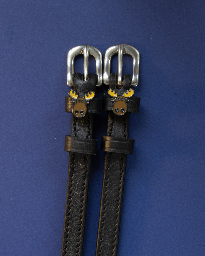 Dark brown leather moose spur straps flat-laid on a navy blue background
