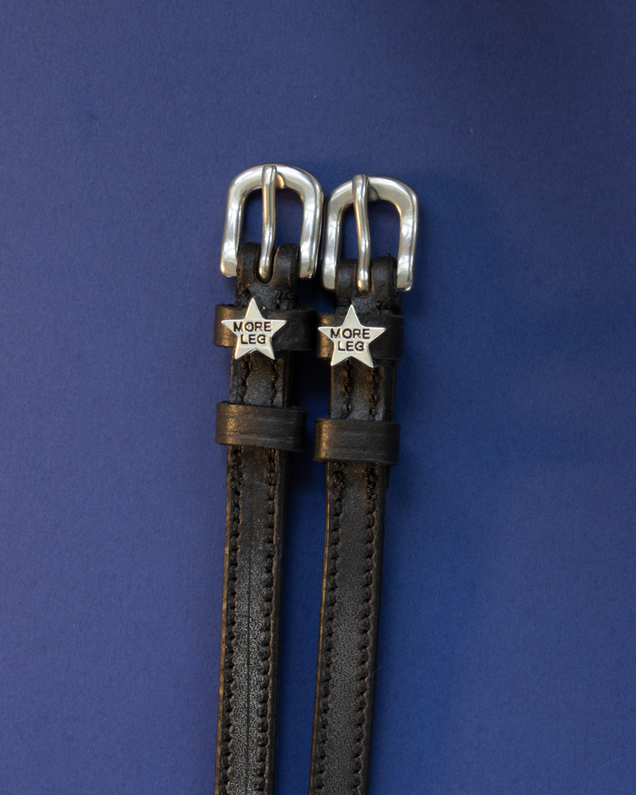 Black leather ManeJane spur straps with silver MORE LEG star charms on navy