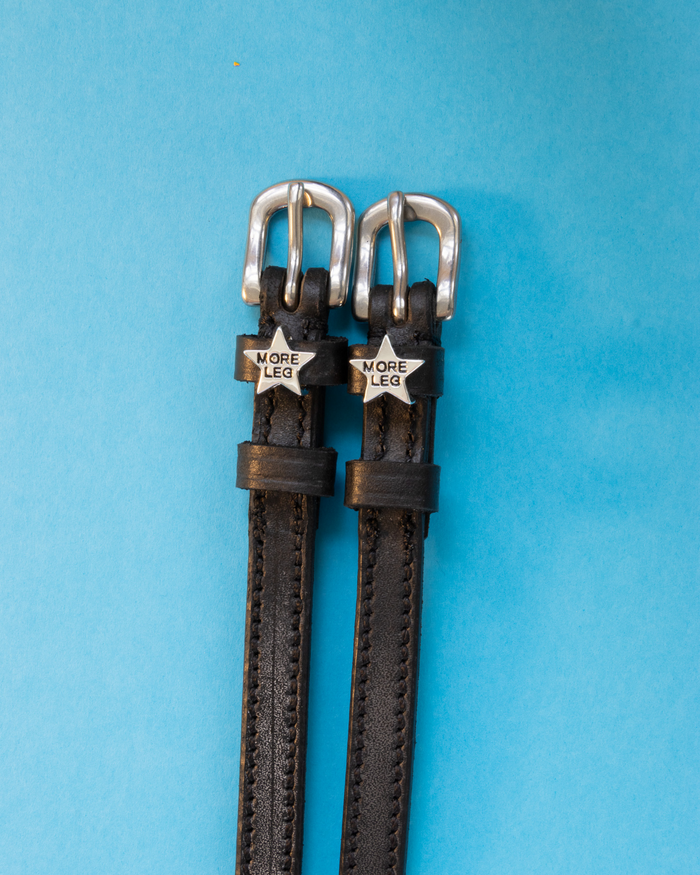 Black leather MORE LEG star spur straps with silver buckles on light blue