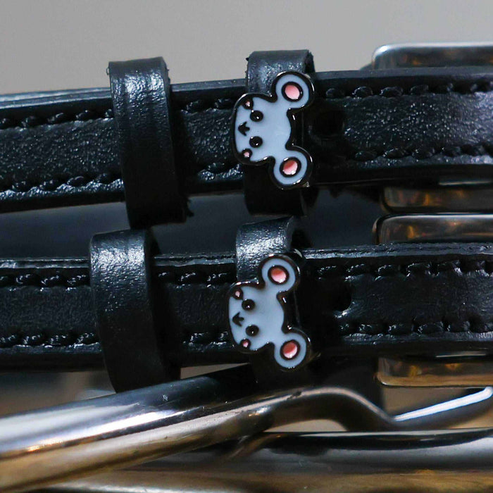 Close-up of grey mouse face charms on black leather spur straps over spur hardware