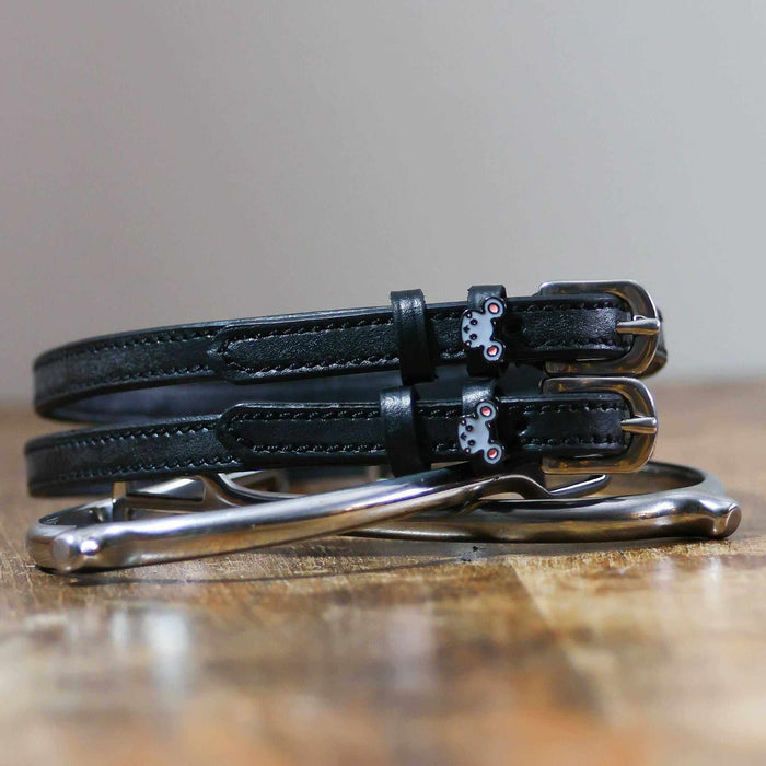 ManeJane Mouse spur straps coiled beside silver spurs on a wooden table