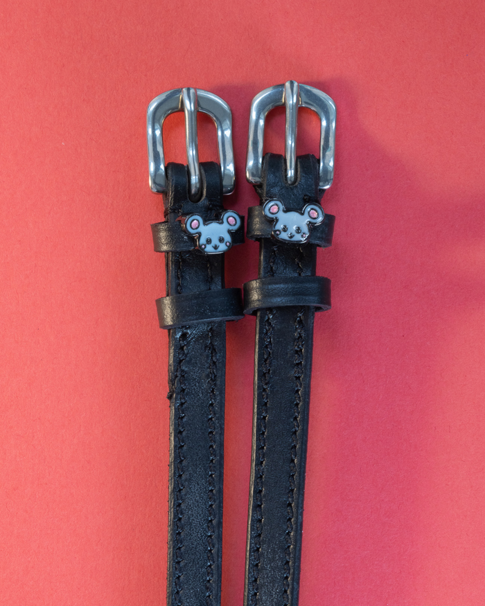 Pair of black leather Mouse spur straps with silver buckles on a coral red background