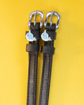 Black leather ManeJane spur straps with blue enamel narwhal charms on a yellow background