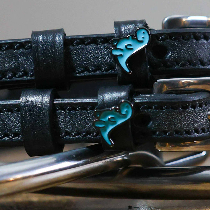 Close-up of teal dinosaur charms on black leather ManeJane spur strap keepers